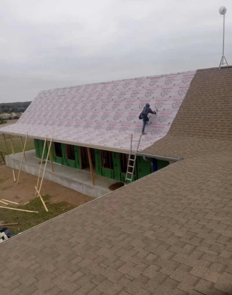 Worker preparing underlayment for a metal roof installation in Brunswick